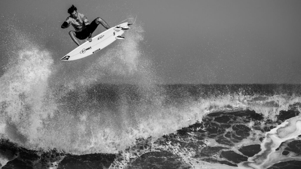 A surfer executing a huge aerial maneuver above the wave in Lacanau, France surf, showcasing skill and style