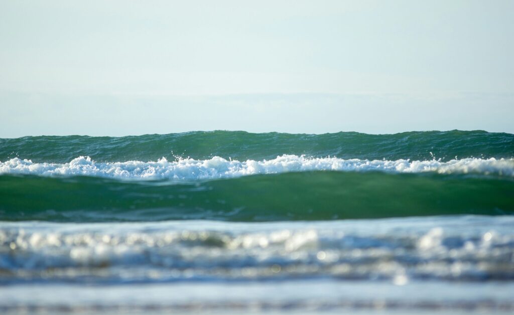 Rolling green-blue waves captured from a low angle in Lacanau surf, France