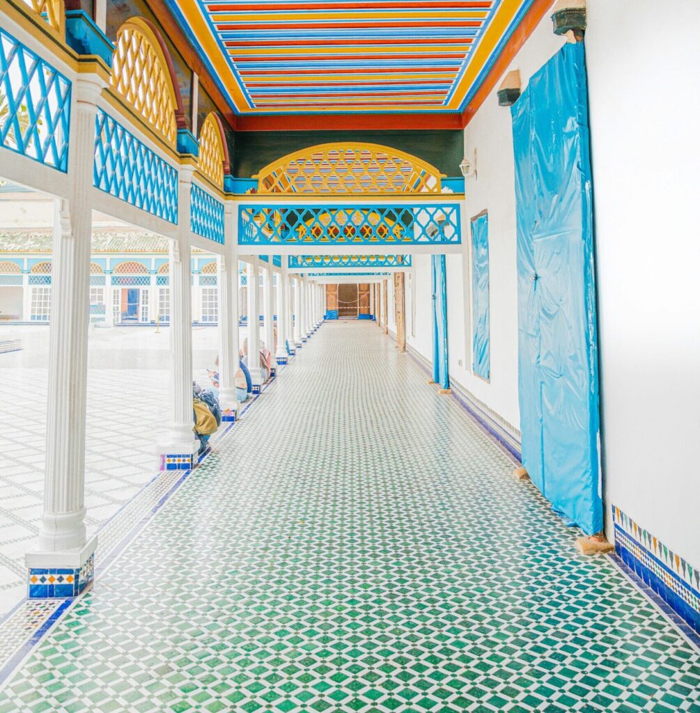 Colorful corridor of Bahia Palace in Marrakech, featuring vibrant patterned tiles and a beautifully painted ceiling