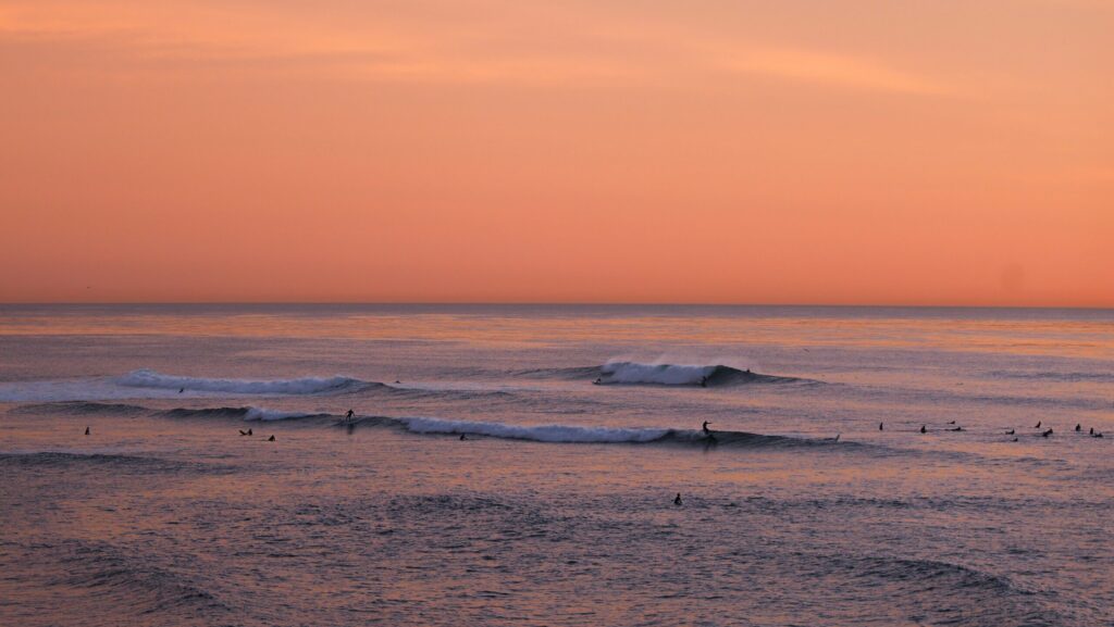 Surfers in the distance catching waves at Sunset Cliffs surf in USA surf