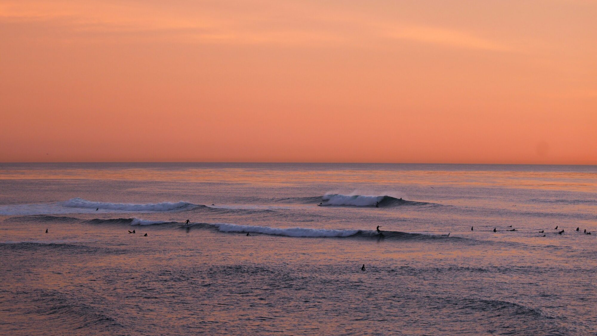 Surfers in the distance catching waves at Sunset Cliffs surf in USA surf
