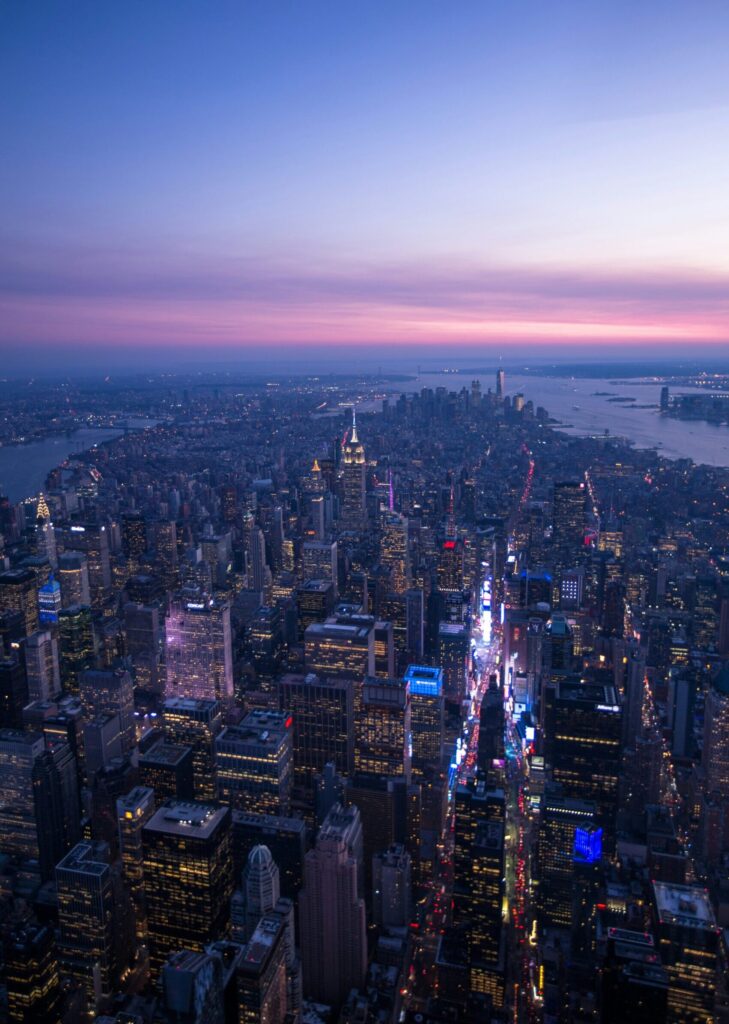 Drone image of New York city with a red and blue sky with building night lights