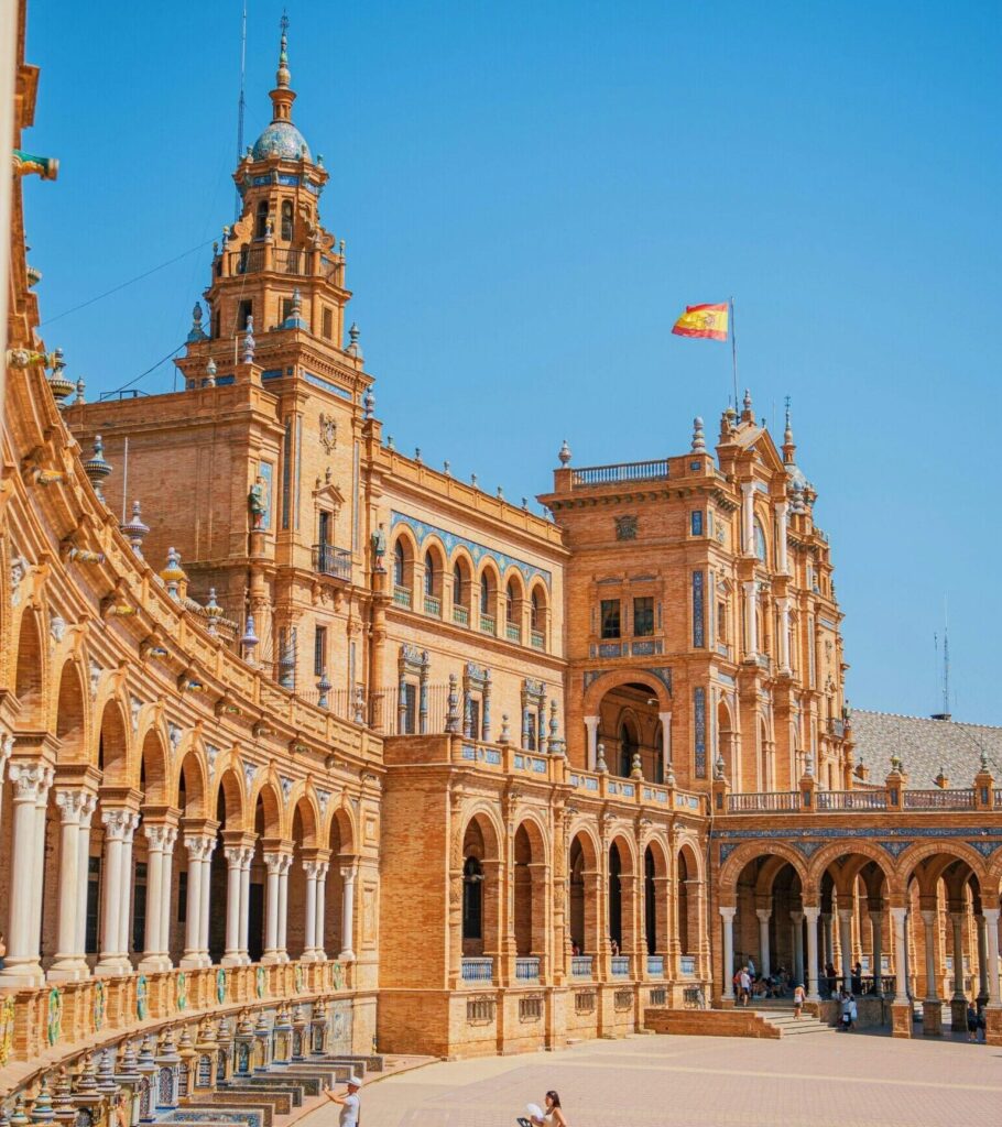 Plaza de España curves to the left, showcasing its architectural details under clear blue skies.