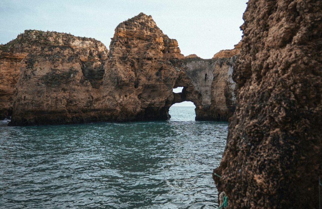 Cliffs with an opening leading to the ocean under clear skies at Cabo de São Vicente - Sagres, showcasing rugged rock formations