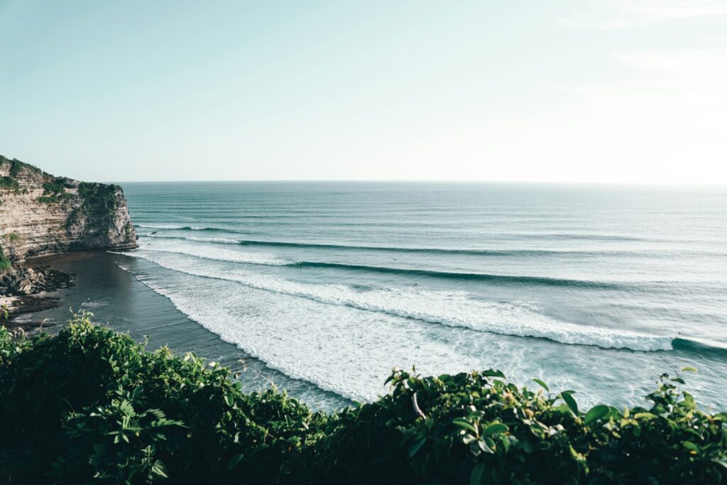 Long left-hand wave sets at Uluwatu surf, Indonesia, with clean blue water and clear skies