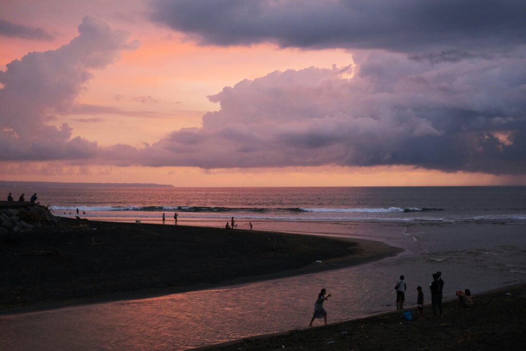 High view of Canggu Surf Beach, Indonesia, with reddish cloudy skies, distant waves, and sandy shoreline