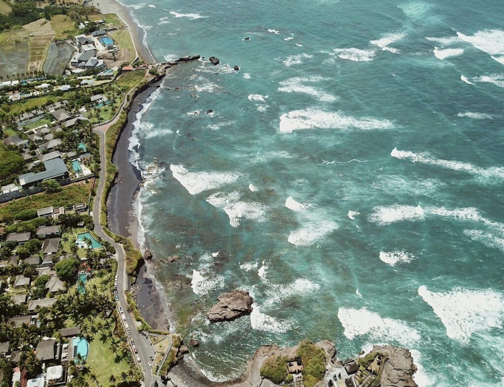 Drone view of Canggu Beach, Indonesia, showing houses on the left and beach with swells on the right