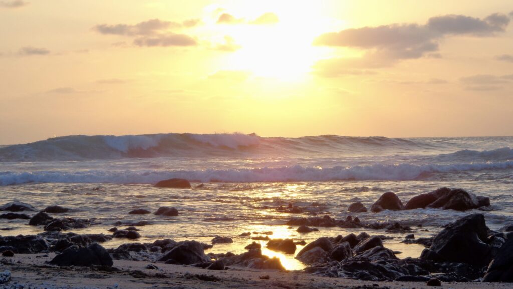 Troncones Point in Troncones surf, Mexico, showing a left-hand wave with the sun in the background creating a yellow backdrop
