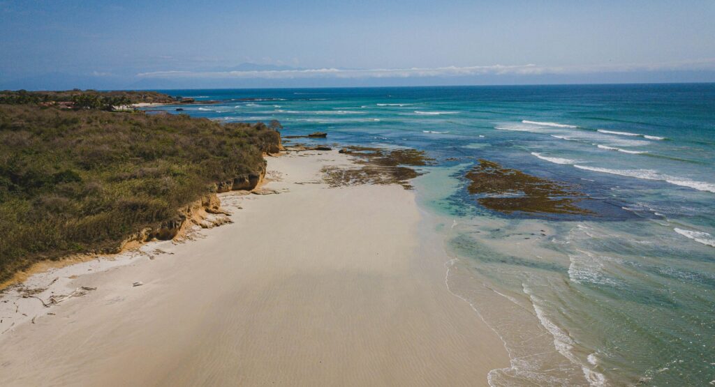 View of Playa La Lancha in Punta Mita surf, Mexico, with sandy shores, calm blue waters, and a clear sky