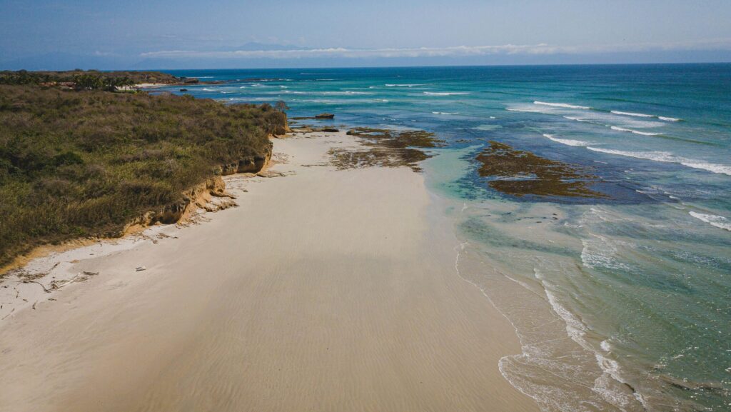 View of Playa La Lancha in Punta Mita surf, Mexico, with sandy shores, calm blue waters, and a clear sky