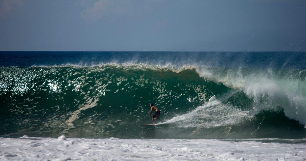 A surfer riding a perfect right-hand wave at Playa Zicatela, Puerto Escondido surf, looking down the line with sunny skies and blue water