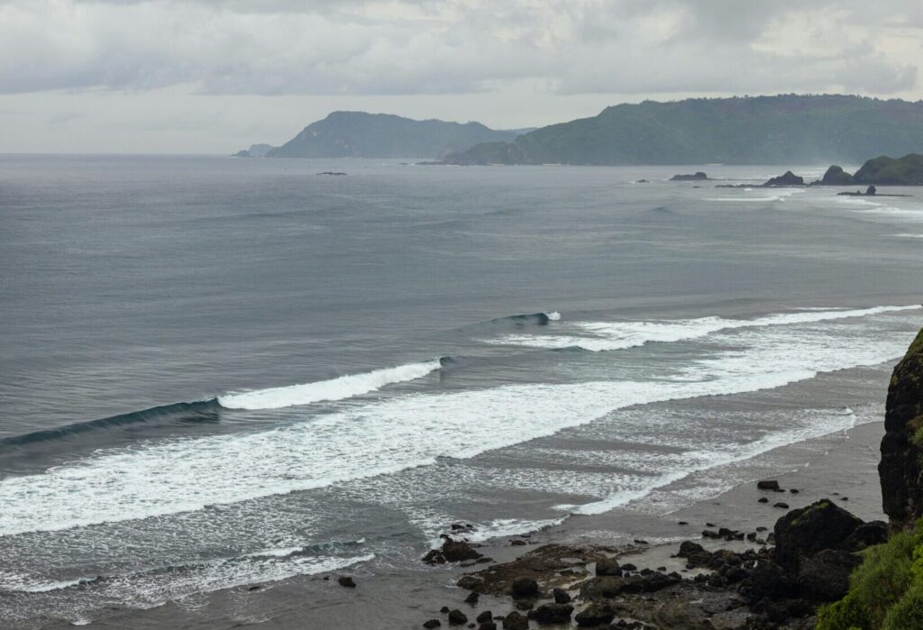 Tanjung Aan Beach, Lombok Surf, with waves breaking under cloudy skies and an empty surf