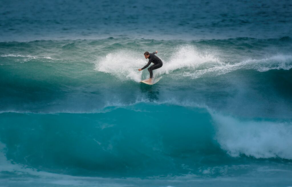 A surfer on a right-hand wave at Watergate Bay, Newquay surf, looking down the line over blue water