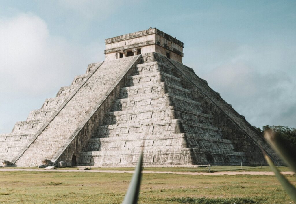 Chichen Itza in Mexico, viewed at an angle with no people, clear skies, and clouds in the background