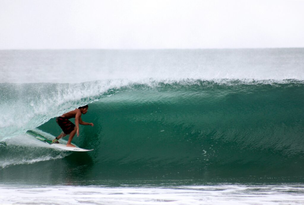 A surfer in a barrel on a right-hand wave at Desert Point Surf, Indonesia