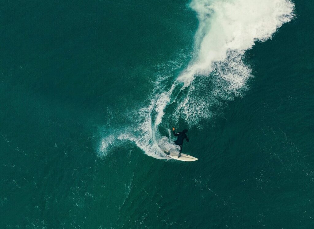 A drone view of a surfer on a right-hand wave with deep blue water at Zarautz Surf Beach, Spain