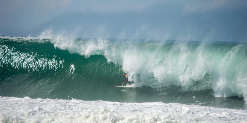 A surfer in a perfect right-hand barrel at Playa Zicatela, Puerto Escondido, looking down the line with sunny skies and blue water.