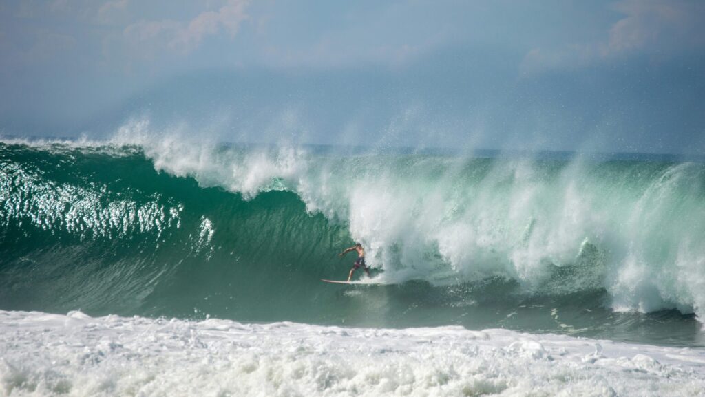 A surfer in a perfect right-hand barrel at Playa Zicatela, Puerto Escondido surf, looking down the line with sunny skies and blue water.