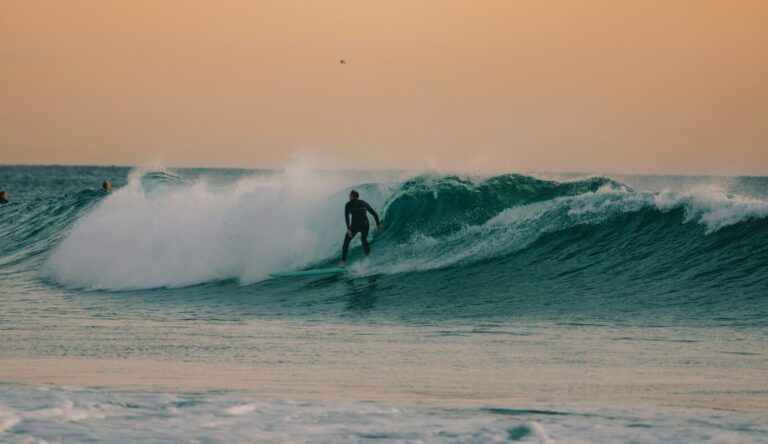 A surfer riding a wave under orange-yellow skies, looking down the line, with no one else around La Saladita surf - Mexico