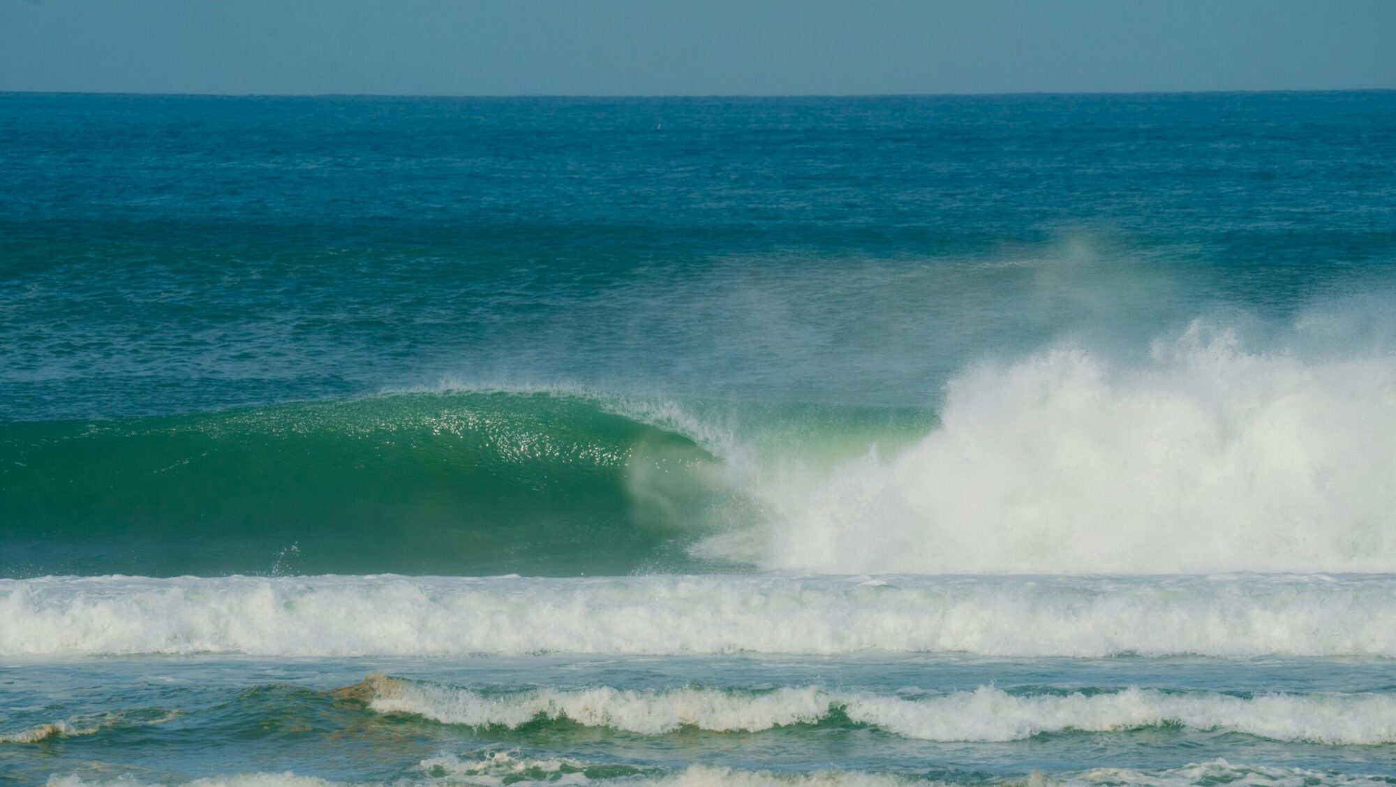 An empty barrelling wave at Barra de la Cruz, Mexico, with clear skies, taken from the beach