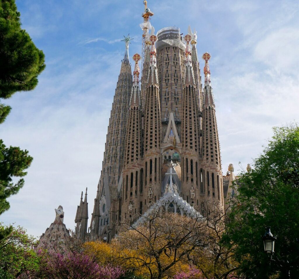 The La Sagrada Familia in Barcelona showing clear blue skies and trees in the foreground