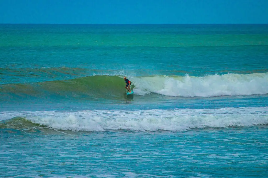 Small right-hand wave at Seminyak surf Beach, Indonesia, with clear skies and surfer riding wave