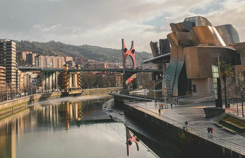 Bilbao city skyline with a cloudy sky, water, and a bridge in the distance