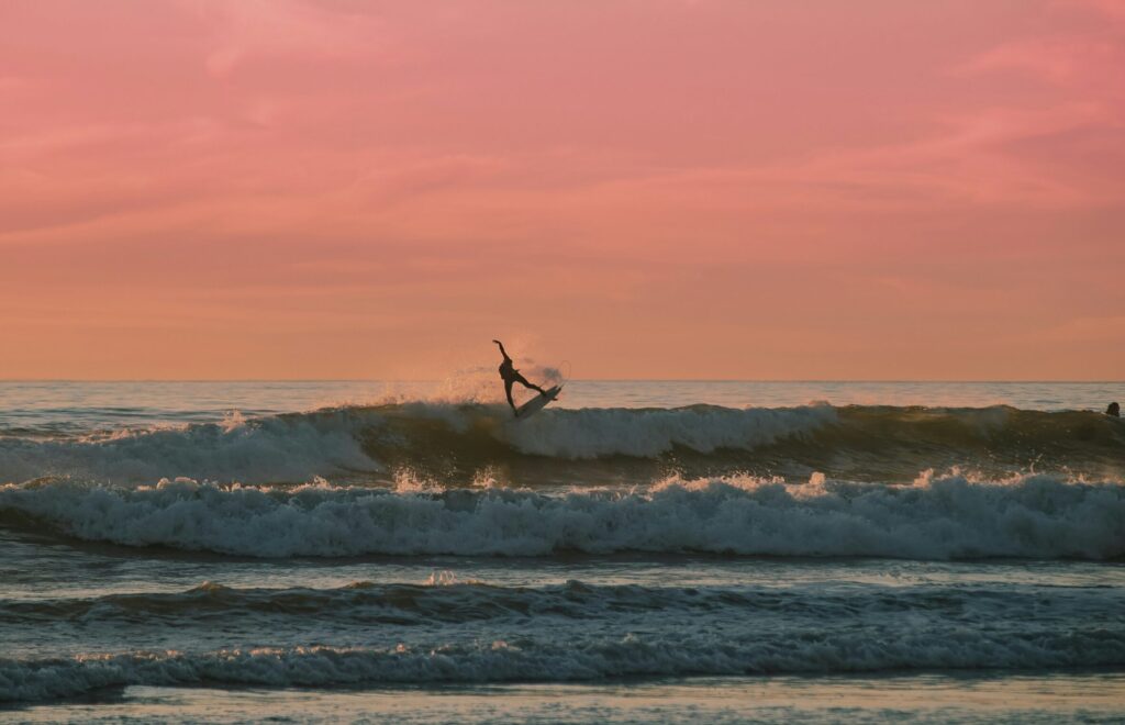 A surfer pulling an air on a left-hand wave in Mexico, with a red sky in the background