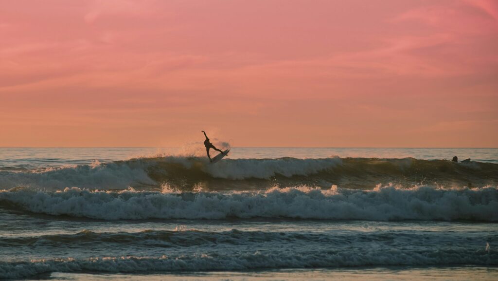 A surfer pulling an air on a left-hand wave in Mexico surf, with a red sky in the background in Sayulita surf
