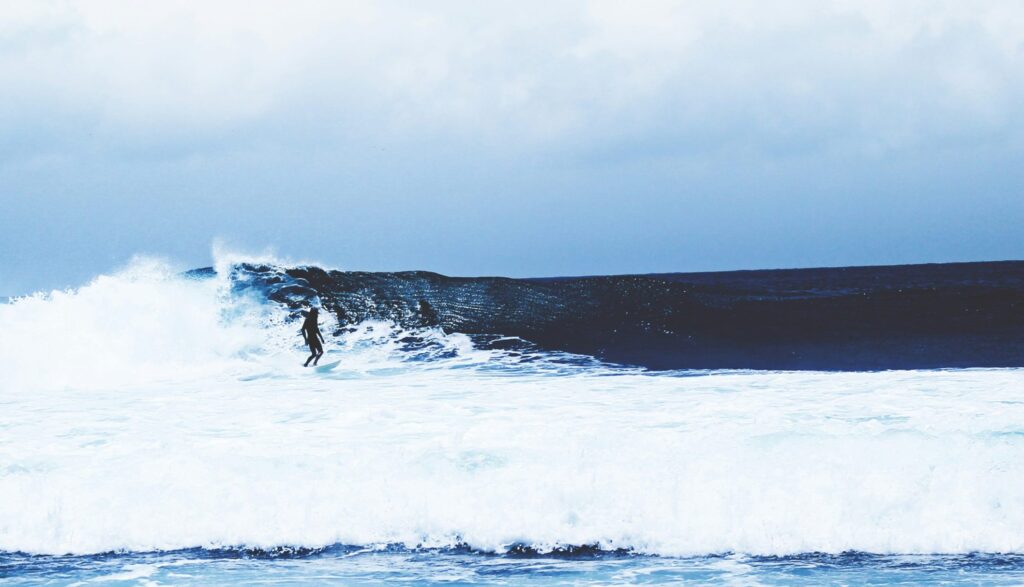 Surfer rides a left-hand wave at Desert Point surf, focused down the line