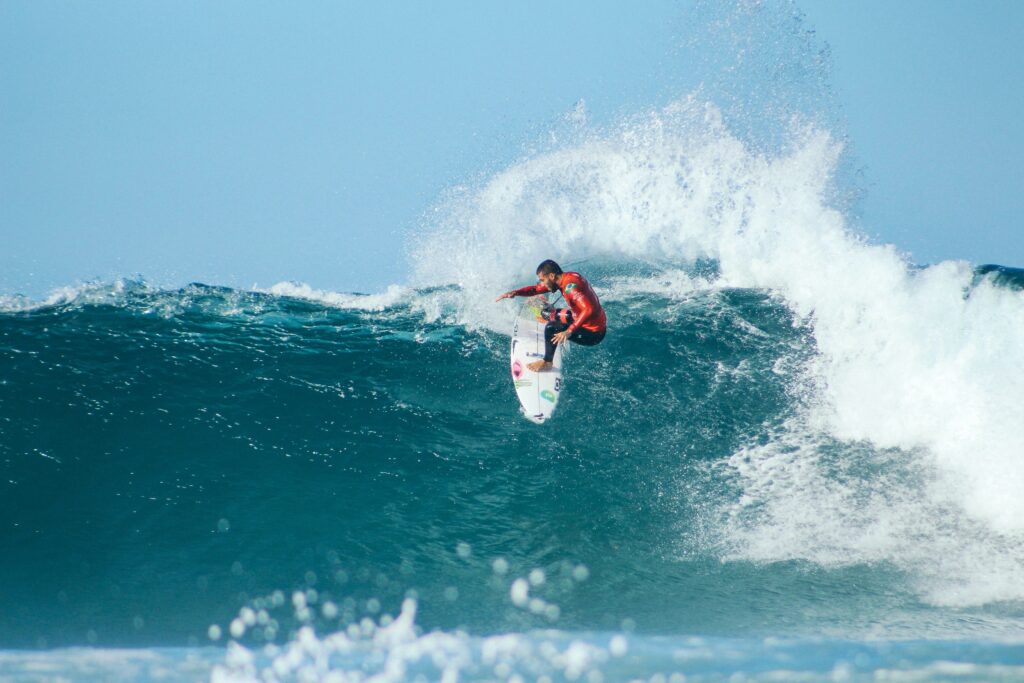 A pro surfer executing a huge turn with lots of spray on a right-hand wave at Jeffreys Bay Surf, South Africa Surf