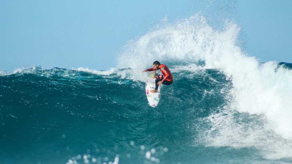 A pro surfer executing a huge turn with lots of spray on a right-hand wave at Jeffreys Bay Surf, South Africa Surf