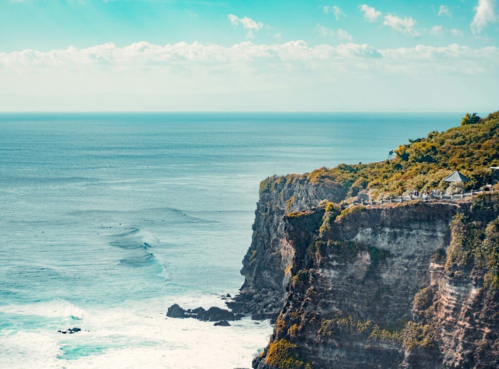 Uluwatu Temple on the cliffs, with the ocean and waves to the left of the image