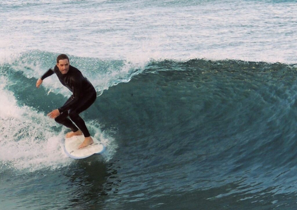 A surfer in a wetsuit riding a perfect left-hand wave, looking down the line in Mundaka Surf, Spain