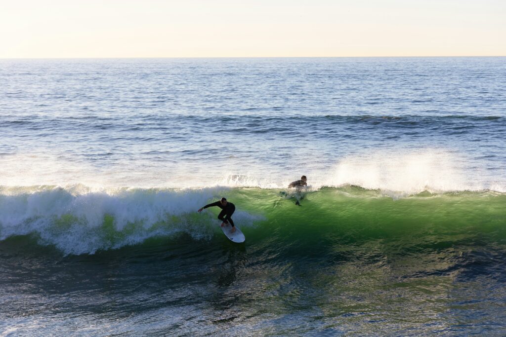 A surfer taking off on a left-hand wave with the surf in Perranporth surf, UK