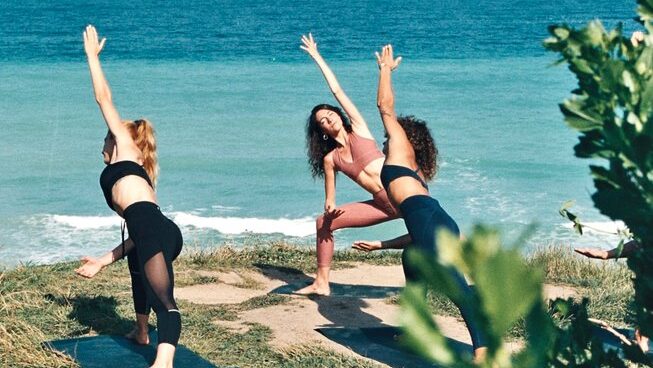 Women practicing yoga with ACOLYTE surf camp