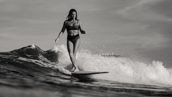 A girl riding a wave in Biarritz surf with ACOLYTE surf camp