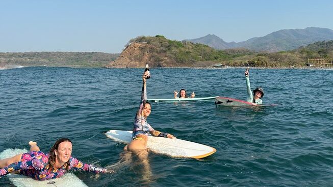 People in the water with beers at Playa Las Flores Surf in El Salvador with SurfXplore Surf camp