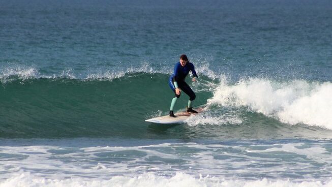A surfer learning how to catch a wave with Jeffreys Bay Surf School and camp