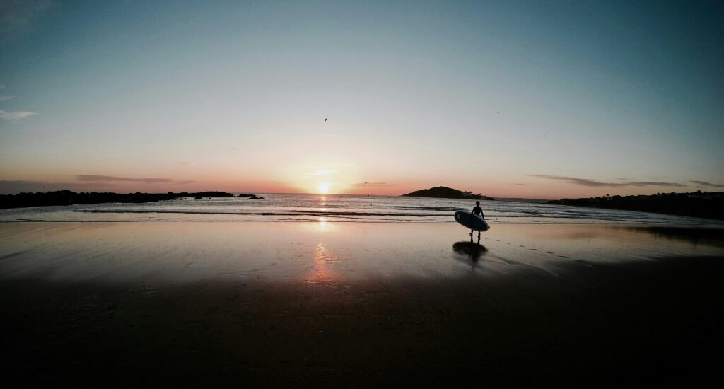 a guy walking to the water with a SUP in Bantham surf, UK
