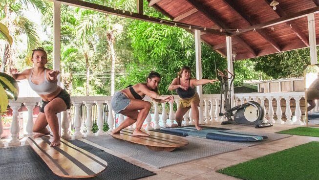Three surfers practicing on land at Mai Ke kai Surf House surf camp Tamarindo Costa Rica