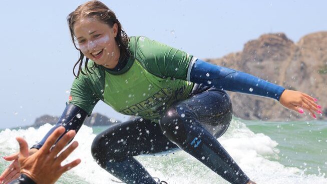 A surfer high fiving at Arrifana surf lodge for a Yoga Surf Retreat Portugal Algarve