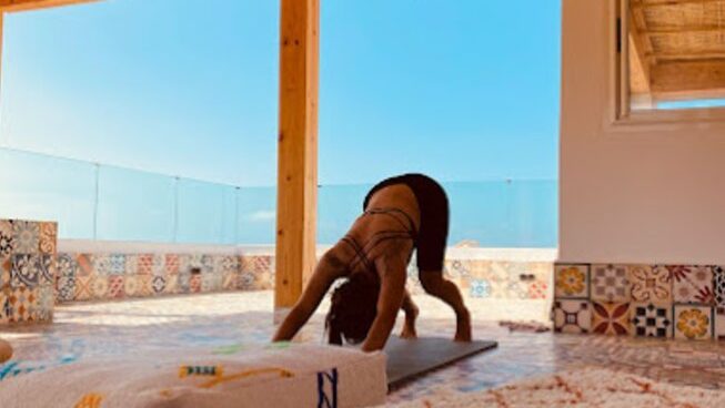 A person doing downward dog at Harmony Surf Lodge Taghzout surf camp