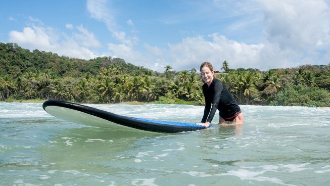 A surfer sitting on a surfboard at Pura Vida Surfers Surf and Yoga Retreat in Santa Teresa
