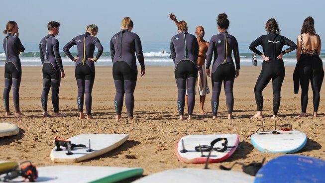 Surfers listening to a teacher at Surf Coast Morocco with Morocco surf camp for beginners