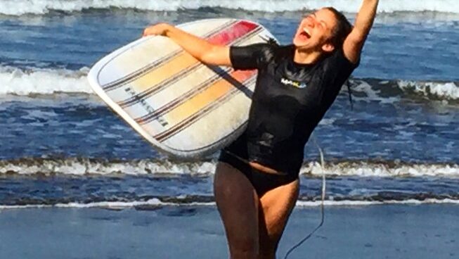 A happy person carrying a surfboard from the beach at Sunset at Surf Inn Hermosa Costa Rica surf camp