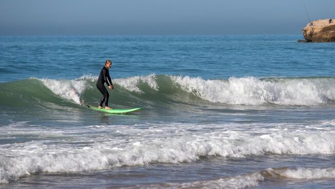 A surfer learning on a wave with Surf & Travel Camp Morocco at a Taghazout surf and yoga retreat