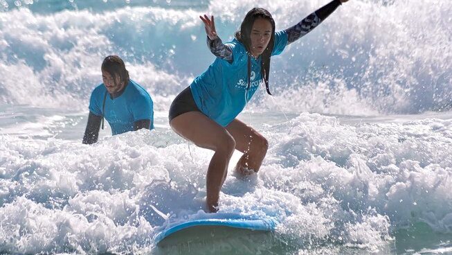 A learner surfer standing up on a wave at Surfescape Fuerteventura in an all inclusive surf camp Canary Islands