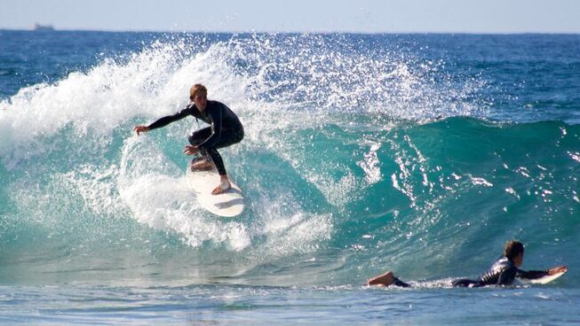 A surfer doing a backside turn at Playa de Las Americas surf The Point Surf Club camp