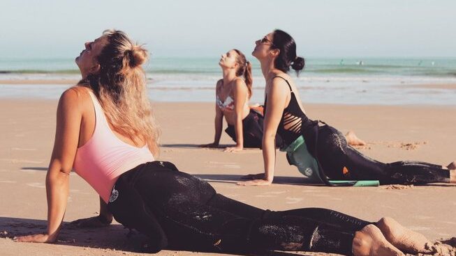 people doing yoga with wetsuits on at Peniche Portugal with Ahoy Surf House surf camp